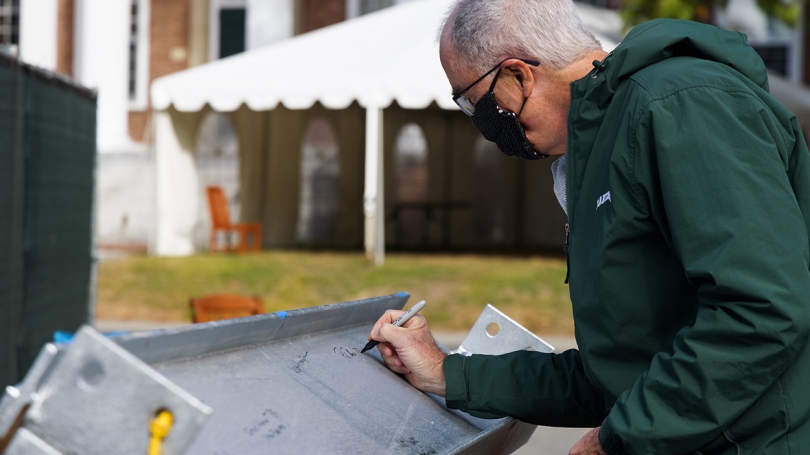 President Philip J. Hanlon '77 signs his name to the final beam.